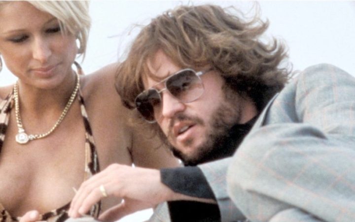 A man sits with a blonde woman in Wonderland.