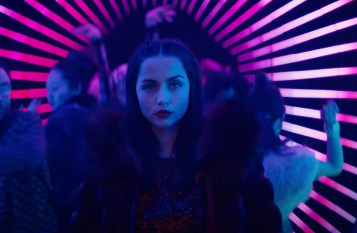 Ana de Armas walks into a neon-lit room.