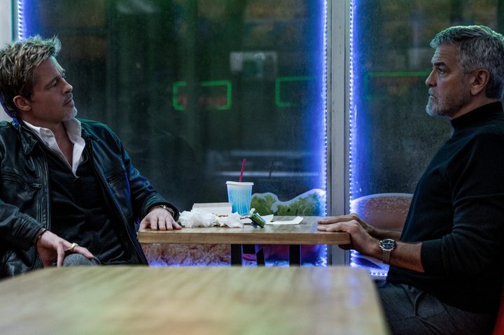 Brad Pitt and George Clooney sit across from each other in Wolfs.