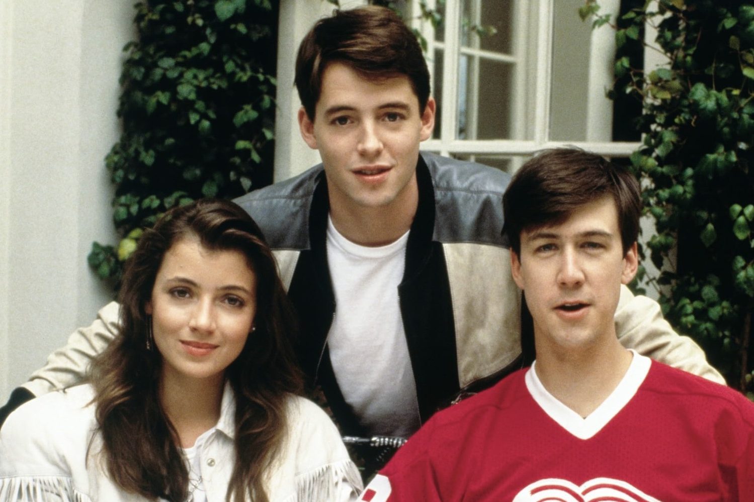 A boy stands over a girl and boy and poses for a picture.