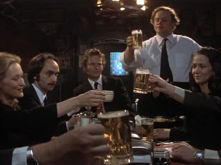 The cast of "The Deer Hunter" sitting at a table holding up beer mugs.