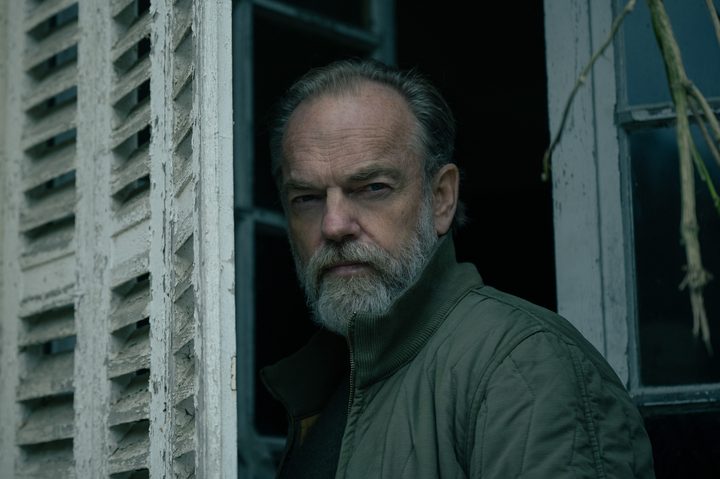 Hugo Weaving stands near old window shutters in Slow Horses season 4.
