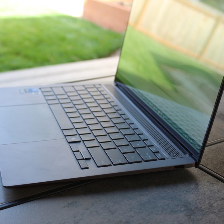 The Asus Zenbook S 14 on a table in front of a grass lawn.