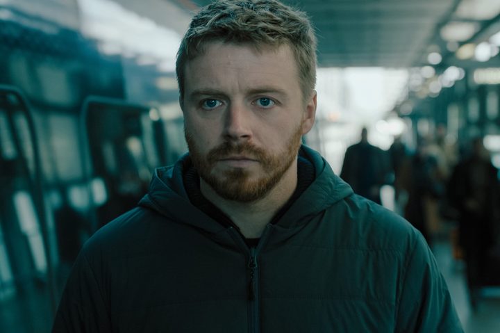 Jack Lowden stands in a train station in Slow Horses season 4.