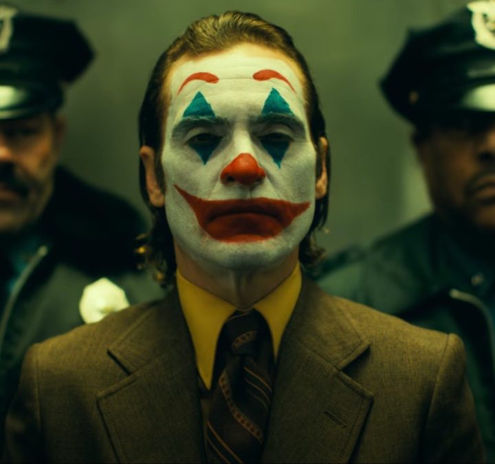A clown stands in front of two cops in an elevator.