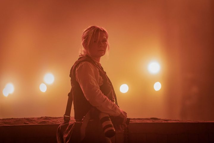 Kirsten Dunst stands near bright lights in Civil War.