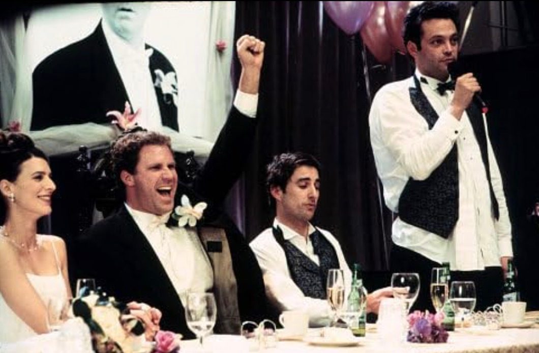 Three men at a wedding table sit next to the bride.