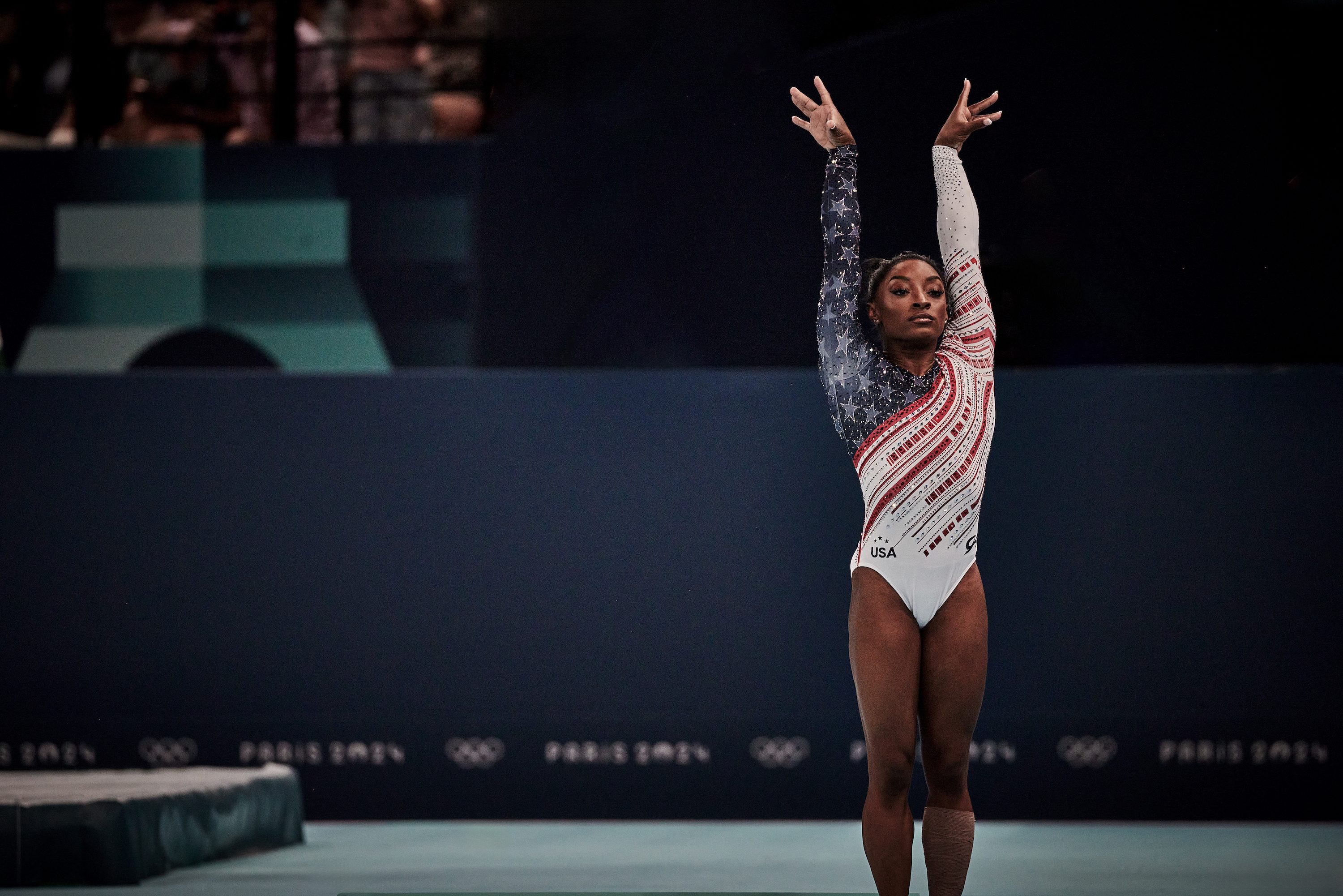 Simone Biles poses with her hands up during a competition.