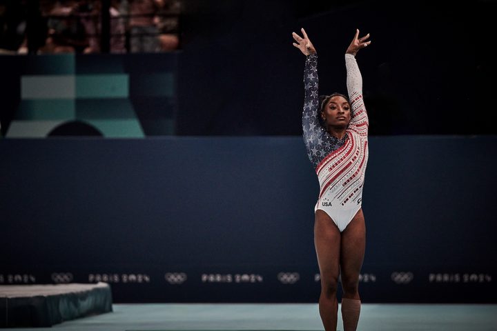 Simone Biles poses with her hands up during a competition.