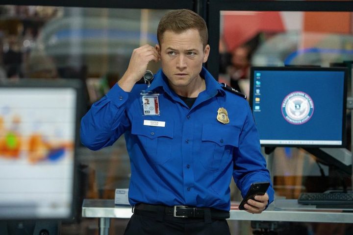 A TSA agent puts an earpiece in his ear.