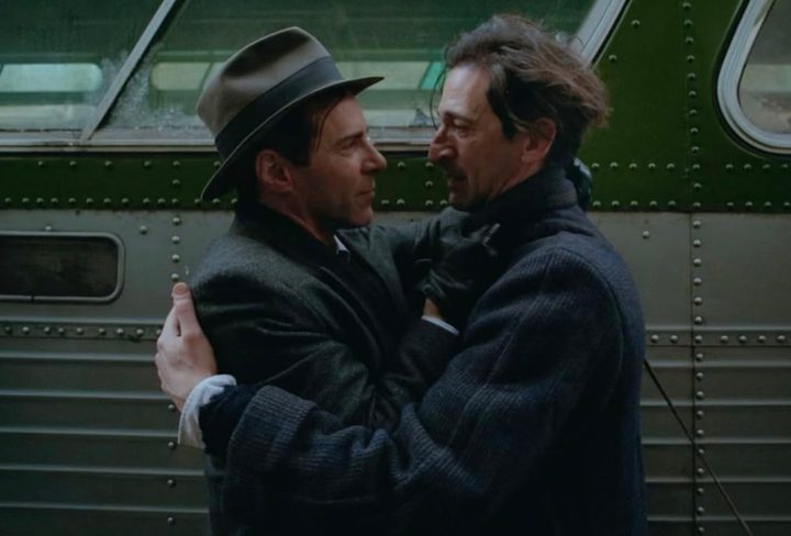 Two men embrace outside of a bus.