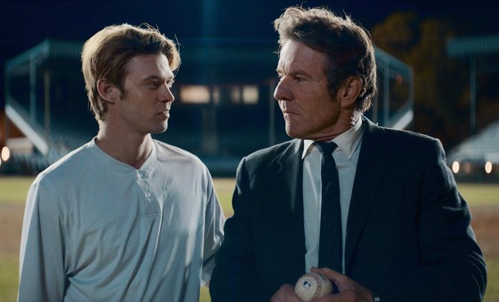 A man and teenager walk next to each other on a baseball field.