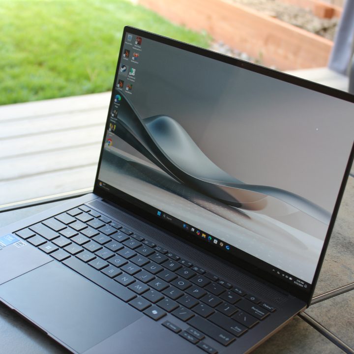 The Zenbook S 14 on a table in front of a grass lawn.