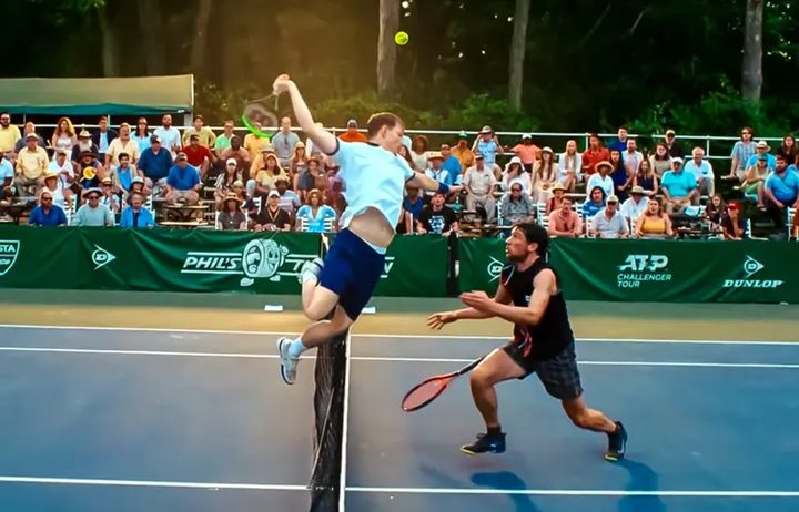 A man leaps across a tennis court net in Challengers.