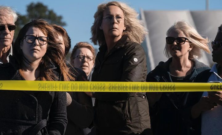 A woman looks from behind police tape in Halloween.