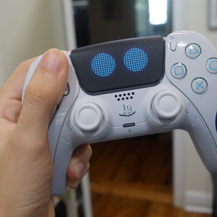 An Astro Bot DualSense being held in one hand.