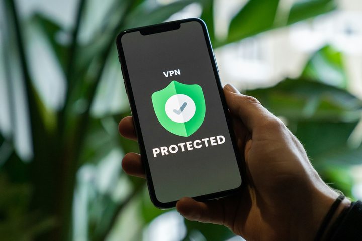 iPhone with VPN service enabled in hand over a blurred background