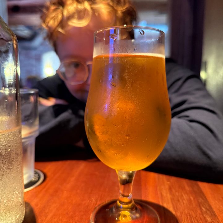 A photo of a beer in a glass at a dimly-lit bar, taken with the iPhone 16 Pro.