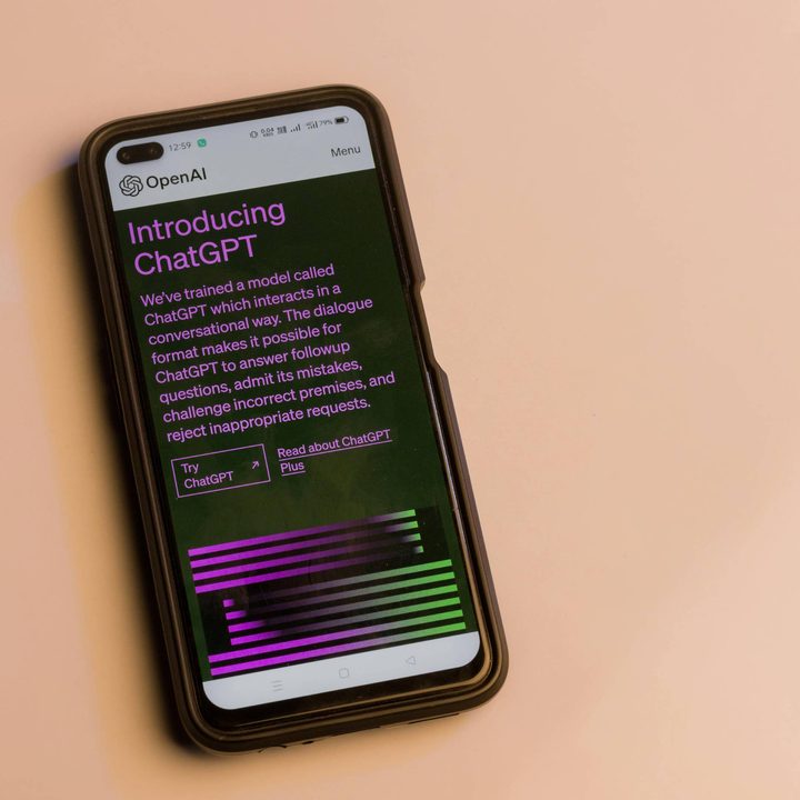 a phone displaying the ChatGPT homepage on a beige background.