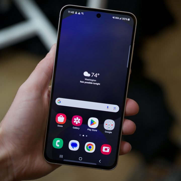 Someone holding the Galaxy S24 FE, showing the phone with the screen turned on.