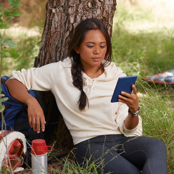 A woman reads on a standard Amazon Kindle.