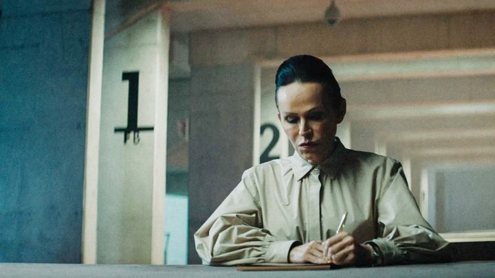 A woman writes on paper in The Platform.