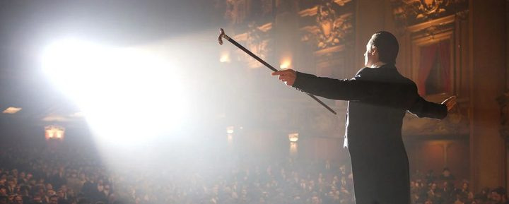 A man spreads his arms on the stage in The Prestige.