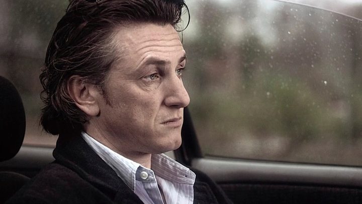 Sean Penn staring into space while sitting in a car in 21 Grams.