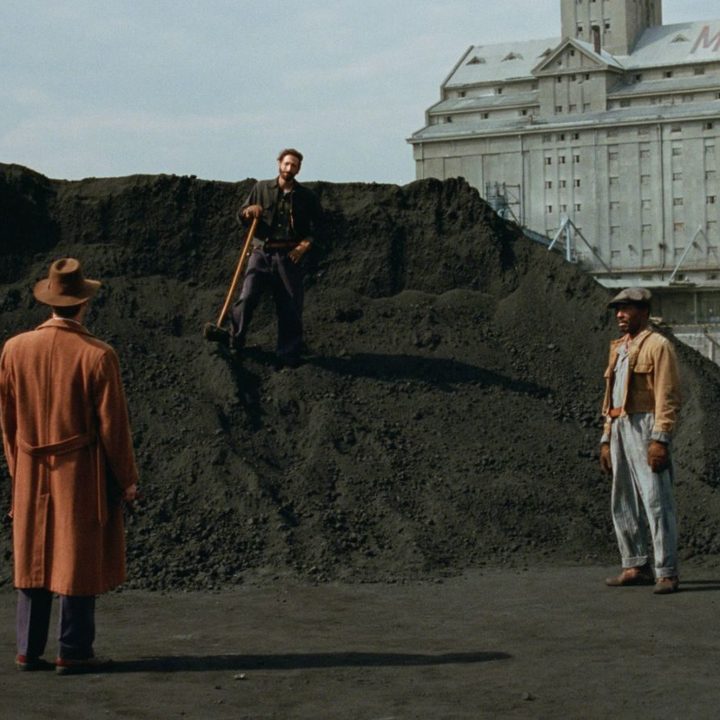 Adrien Brody stands on a pile of dirt in a still from the movie The Brutalist.