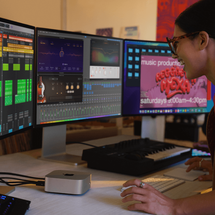A woman using the M4 Mac mini with three monitors connected.