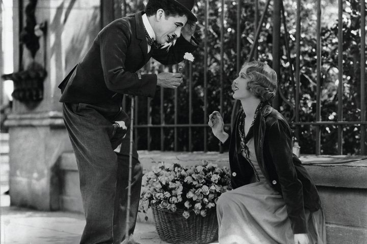 Charlie Chaplin smiles at a flower girl in City Lights.