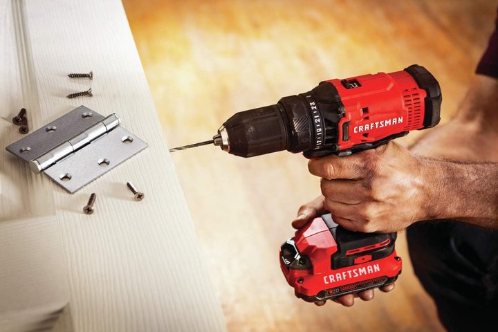 A man using a Craftsman V20 Drill/Driver on a wood door.