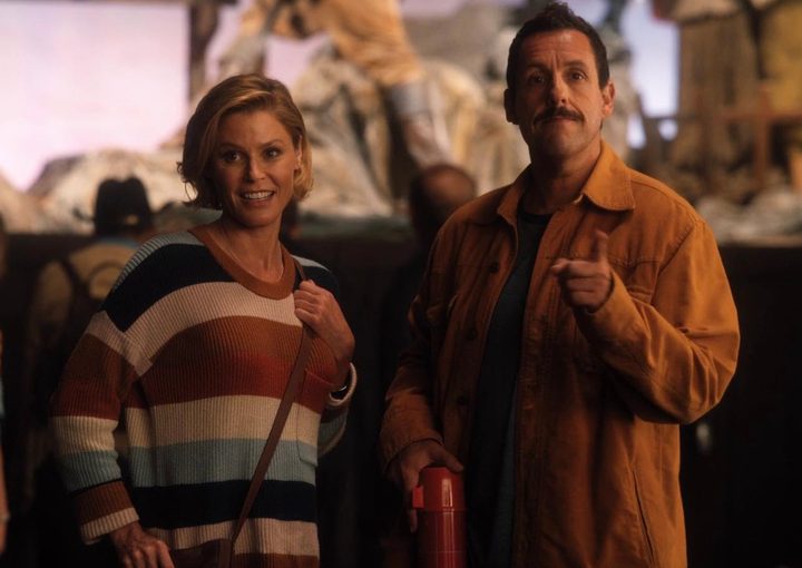 A man and a woman stand next each other and points.