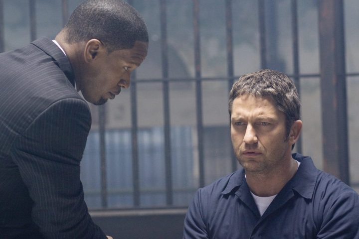 Jamie Foxx speaks to Gerad Butler at a table.