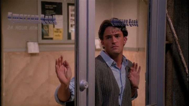 Matthew Perry as Chandler Bing with his cheek pressed against a glass door in Friends.