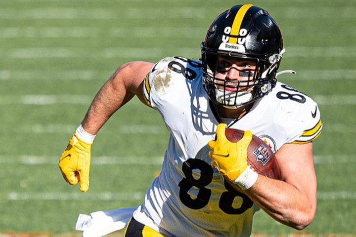A Pittsburgh football player holds a ball and runs.
