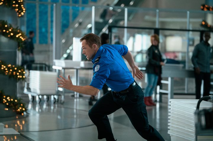 Taron Egerton sprints through an airport.