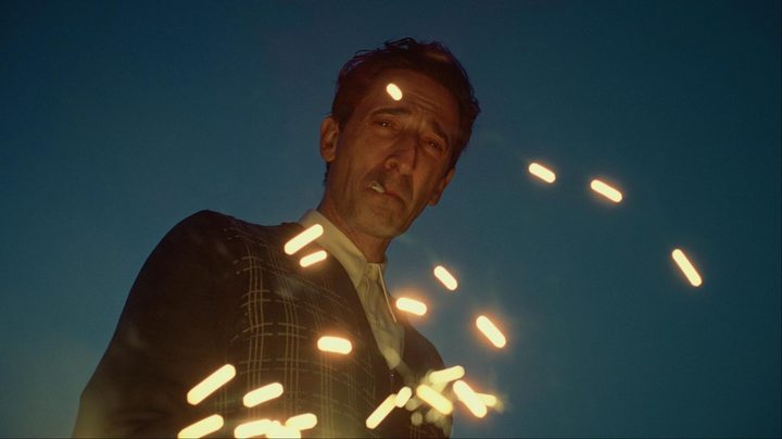 A man smokes a cigarette and looks down.