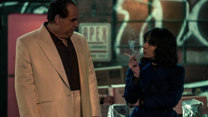 A woman smokes a cigarette as a man stands next to her.