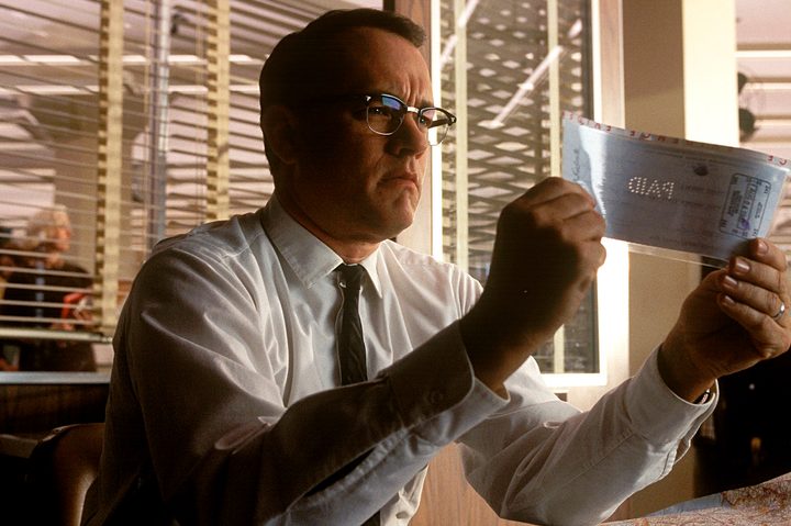 Tom Hanks inspects a check in Catch Me If You Can.