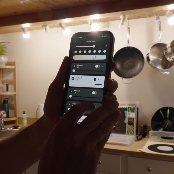 Lighting control on the Vivint app on a phone being held by someone.