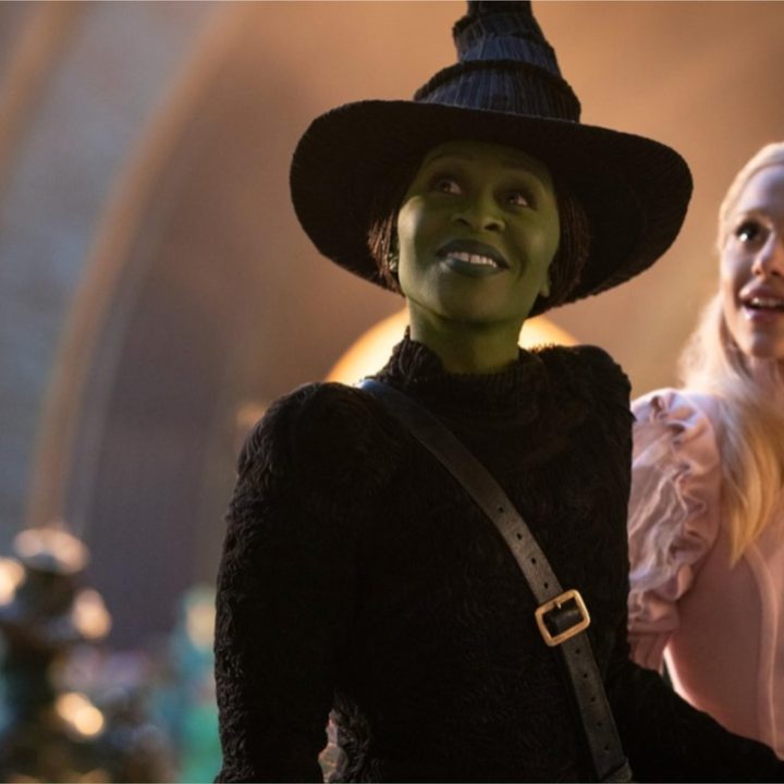 Cynthia Erivo and Ariana Grande smile in a still from the movie Wicked.