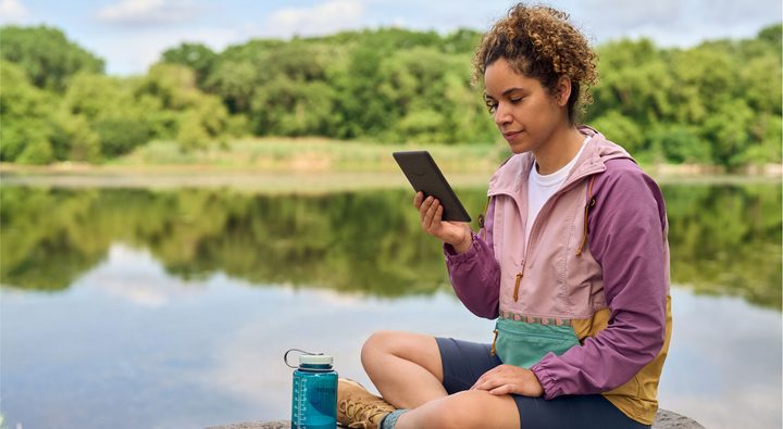 Amazon Kindle Paperwhite 2024 12th-generation being used outside by a lake