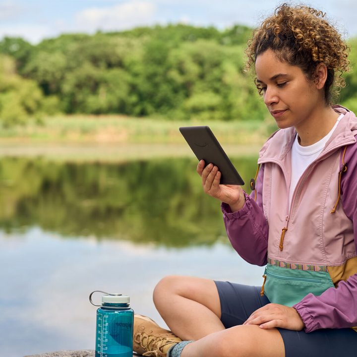 Amazon Kindle Paperwhite 2024 12th-generation being used outside by a lake