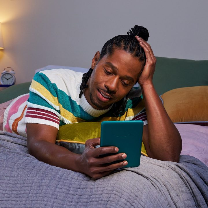 Amazon Kindle Paperwhite 2024 12th-generation jade in-use while lying on stomach on a bed