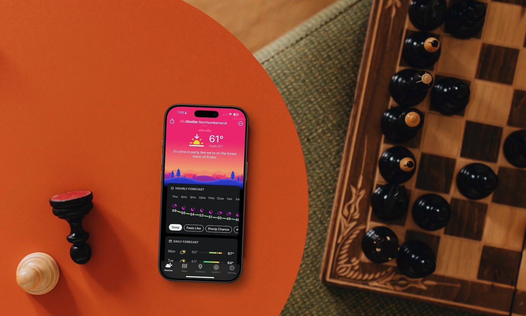 Carrot Weather app on iPhone on table next to chess board.