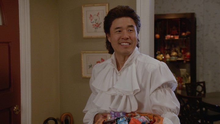 Louis from Fresh Off The Boat dressed like Seinfeld with longer hair and a white puffy shirt.