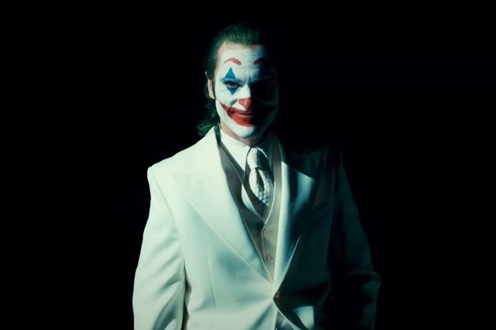 A man in white suit smiles in Joker: Folie a Deux.