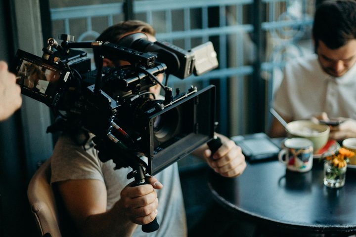 A man holding a video camera in a cafe.