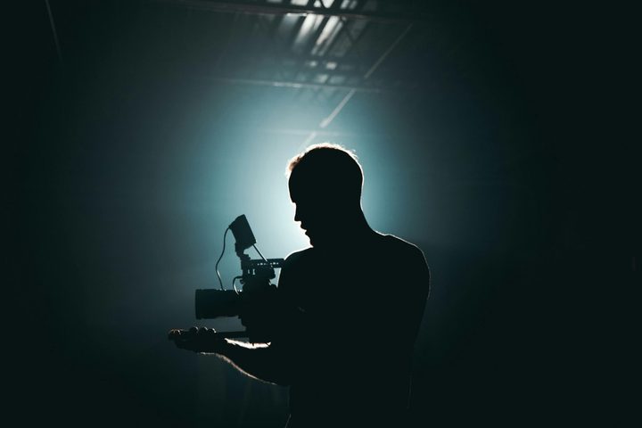 A man holding a video camera in the dark.
